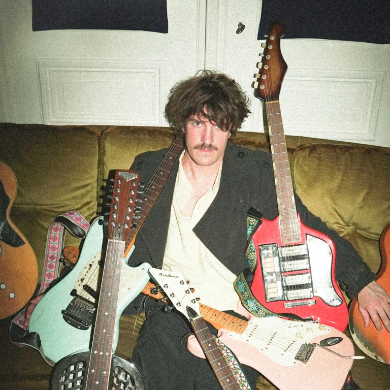 Foto: Vitja Pauwels omgeven door elektrische gitaren | Olympe Tits